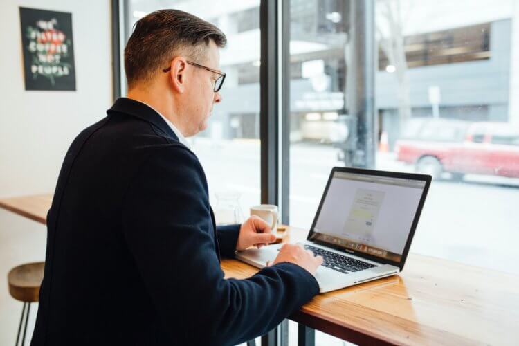 A photo of a man working on his laptop at a cafe