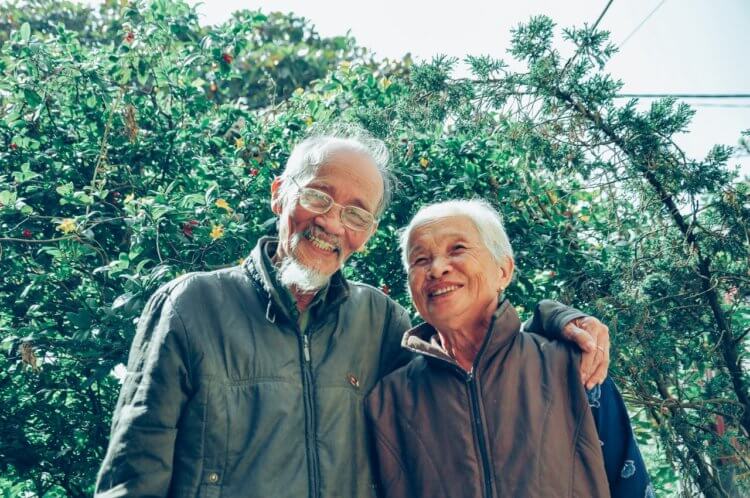 elderly couple in front of trees