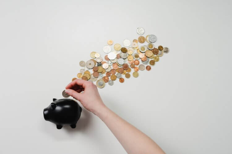 Person putting coins into a piggy bank
