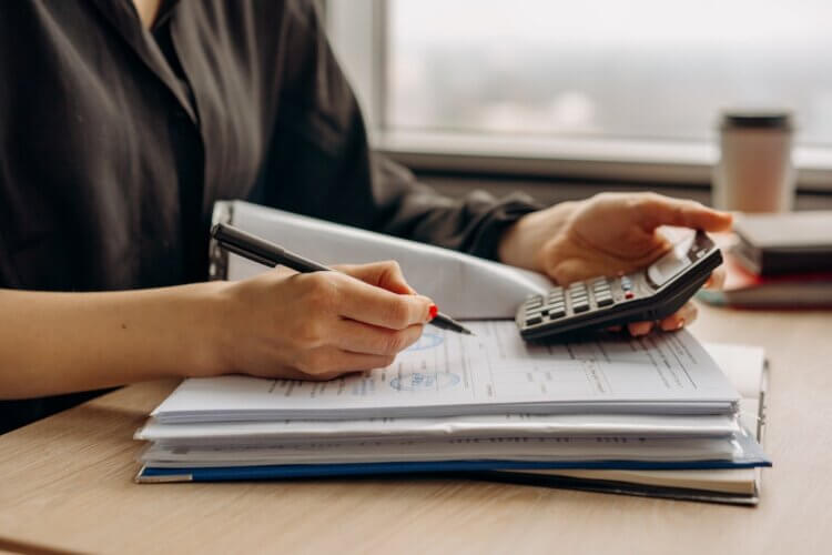 law firm accountant writing at a desk with calculator