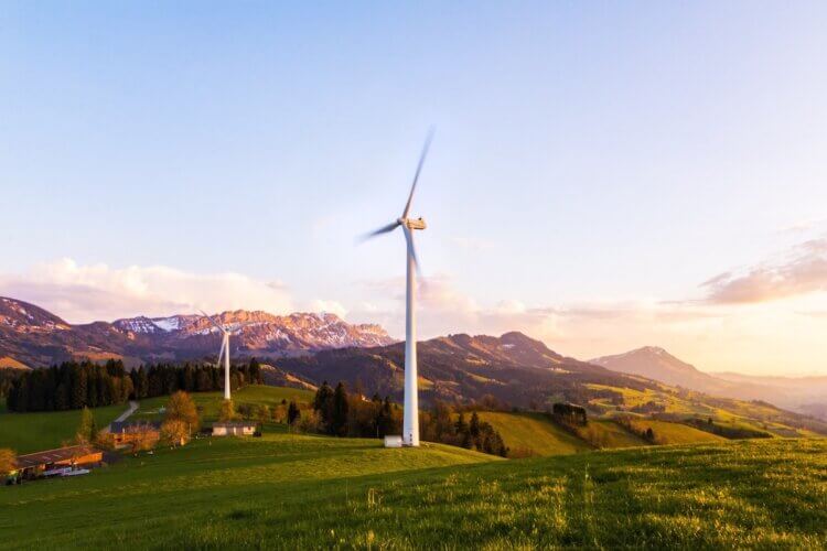 Windmill on grassy land in front of mountains